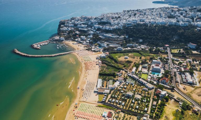 Veduta aerea di una città costiera con spiaggia e porto.