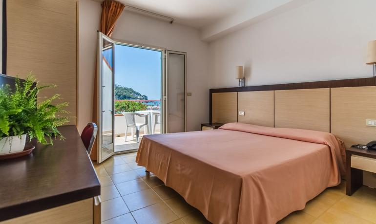 Camera con vista mare, balcone e arredi moderni.