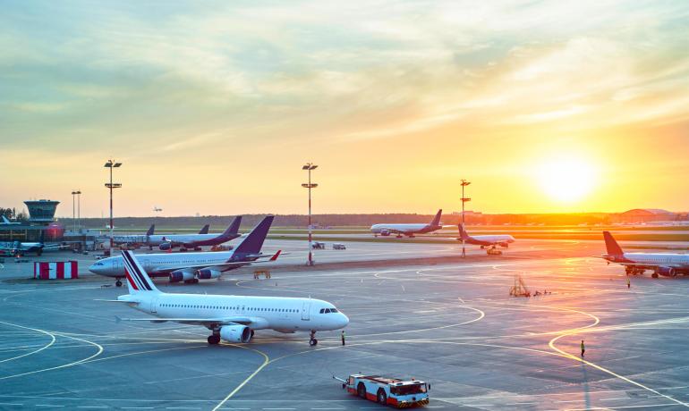 Aeroporto al tramonto con aerei sulla pista.